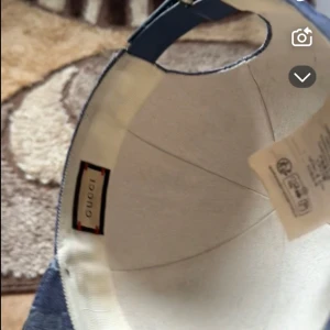 Blå Gucci keps i jeans med monogram - Snygg blå keps från Gucci i jeansmaterial med klassiskt GG-monogram över hela kepsen. Böjd skärm och justerbar baksida. Perfekt för dig som vill sticka ut med en exklusiv streetstyle-look.