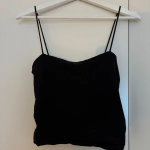 Svart linne från Gina Tricot - Supersnygg svart linnetopp från Gina Tricot i mjukt material. Toppen har tunna axelband och enkel, stilren design som är lätt att matcha. Perfekt för dig som gillar minimalistisk och trendig stil.