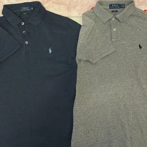 2 st Polo Ralph Lauren pikétröjor slim fit - Två klassiska Polo Ralph Lauren pikétröjor i slim fit-modell. En är marinblå med ljusblå broderad logga, den andra är gråmelerad med svart logga. Båda har krage, knappar framtill och korta ärmar. Perfekta för en clean och stilren look.