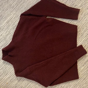 Mörkröd stickad polotröja från Zara - Säljer en mörkröd stickad polotröja från Zara i storlek S. Tröjan har en hög ribbad krage, långa ärmar och breda ribbade muddar vid ärmslut och nederkant. Perfekt för kyliga dagar och enkel att styla med jeans eller kjol.