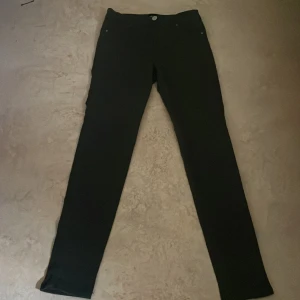 Gröna  slim byxor från 157 Vanna - Gröna byxor från 157 Vanna med slim passform och klassisk femficksdesign. Byxorna har dragkedja och knapp framtill och är tillverkade i ett stretchigt material som sitter tajt längs benen. Perfekta för dig som gillar en stilren och enkel look.