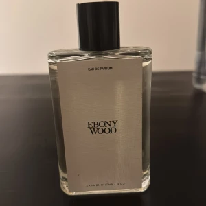 Zara Ebony Wood Eau de Parfum - Ebony Wood Eau de Parfum från Zara Emotions No3. Flaskan är rektangulär i genomskinligt glas med svart lock och stilren vit etikett. Doften har träiga och kryddiga inslag, perfekt för dig som gillar unika och djupa parfymer.