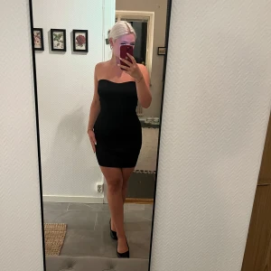 Svart axelbandslös klänning NA-KDo - Säljer en svart, tight och axelbandslös kortklänning från NA-KD. Klänningen har hjärtformad urringning och tyget är lite stickat. Endast använd en gång så fint skick :)