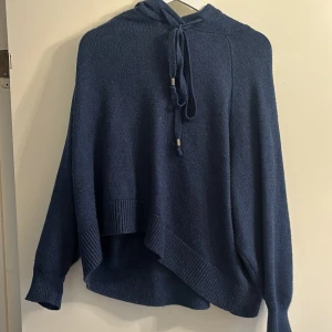 Mörkblå stickad hoodie från L.O.G.G. - Säljer en mysig mörkblå stickad hoodie från L.O.G.G. med en avslappnad passform. Tröjan har långa ärmar och en praktisk huva med knytband. Perfekt för kyliga dagar!