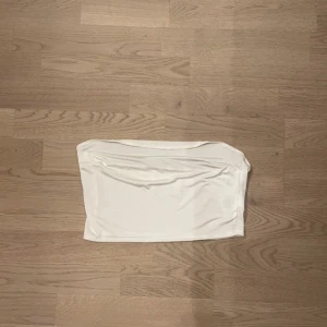 Vit tubtopp - Säljer en stilren vit tubtopp som är helt oanvänd från Nelly. Perfekt för varma sommaren eller som ett basplagg i garderoben. Ska flytta snart så vill gärna bli av med allt så fort som möjligt (pris kan diskuteras)💕