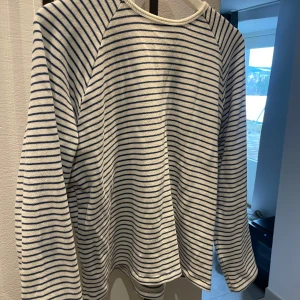 Randig tröja från Zara - Säljer en stilren randig tröja från Zara i vitt och blått. Tröjan har långa ärmar och en klassisk design som passar perfekt för vardagsbruk. Tillverkad i ett mjukt och bekvämt material.
