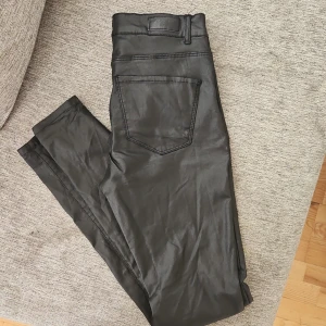 Svarta byxor med fickor - Snygga svarta byxor med fickor och en stilren design. Perfekta för en modern look. Byxorna har en rak passform och är tillverkade i ett material som ger en lätt glansig yta.