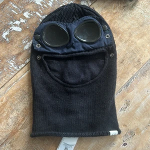 Svart stickad balaclava från C.P. Company - Skit fet C.P company balaclava. Oanvänd. Köpte den för 1,5 år sen av ingen anledning och har inte använt den sedan dess. Inköpt för: 1800kr; pris nu 500. Bara att höra av sig vid frågor!