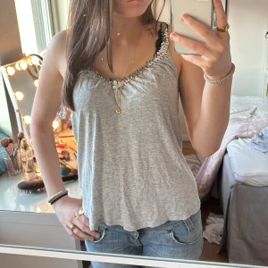 Ljusgrått linne med paljettband från H&M - Super fint ljusgrått linne med paljettband och en lös passform från H&M. Den är i storlek 36-38 men passar mig som är xs/s. Den har inga defekter. Använd gärna köp nu💕