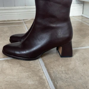 Bruna skinnstövletter med dragkedja - Snygga bruna stövletter i skinn med dragkedja på sidan. De har en bekväm klack och en stilren design som passar perfekt till höstgarderoben. Använda några gånger men kommer inte till användning. Lite skadad se bild 3. 