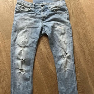 Dondup George Jeans - Snygga ljusa jeans från George med slitna detaljer för en trendig look. De har en slim passform och klassisk femficksdesign. Perfekta för en avslappnad stil.