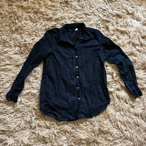 Svart långärmad skjorta - Svart långärmad skjorta med knappar framtill. Den är lite transparent.
