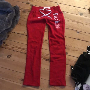 Röda lågmidjade mjukisbyxor från Abercrombie Kids - Säljer ett par röda lågmidjade mjukisbyxor från Abercrombie Kids med vit snörning i midjan och tryck på benet. Perfekta för en avslappnad stil. Det står storlek m för barn men skulle säga att den är xxs-xs