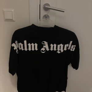 Svart tröja från Palm Angels - Snygg svart tröja från Palm Angels med deras ikoniska logga i vitt på ryggen och mindre på framsidan vid halsen. Perfekt för en stilren look.