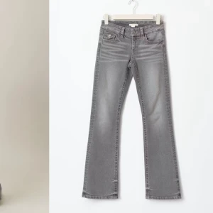 Grå bootcut jeans - Snygga grå bootcut jeans och klassisk femficksdesign. Jeansen har en stilren look med knappar och dragkedja framtill. Perfekta för en avslappnad men trendig stil.