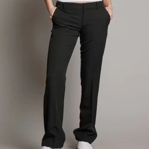 Svarta kostymbyxor (vera) - Snygga svarta kostymbyxor med en klassisk design. De har en rak passform och är perfekta för en stilren look. Byxorna har en dragkedja och knappar framtill.