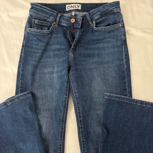 Bootcut jeans från ONLY - Snygga blå jeans från ONLY med klassisk femficksdesign och knappgylf. Perfekta för en avslappnad stil. Märkesdetaljer på knappen och baksidan. Bootcut. Säljer då de är för korta för mig. Storlek: m/30 medelhög midja