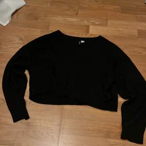 Säljer en svart croppad tröja från H&M Divided. Tröjan har en v-ringad design och är tillverkad i ett mjukt material. Passar bra till jeans eller kjol.