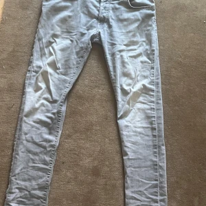 Ljusgrå jeansbyxor från Jacob Cohen - Snygga ljusgrå jeansbyxor från Jacob Cohen med en klassisk femficksdesign. Byxorna har en slim fit passform. Ostryckna på bilderna men kommer såklart stryka dem innan köp. Det är det påväg till ett hål på bild 3 annars så är skicket bra. Storlek är 34/34 och sitter true to size