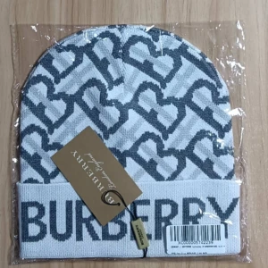 Vit och grå mössa från Burberry - Snygg vit och grå mössa från Burberry med ett stilrent hjärtmönster. Mössan har en uppvikt kant med Burberry-loggan i grått. Perfekt för att hålla sig varm med stil.