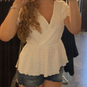 Vit blus Vero Moda - vit omlottblus med spetsdetaljer och korta ärmar och v-ringning.