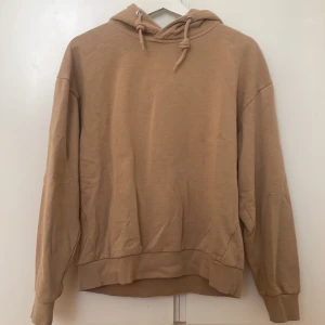 Beige hoodie - Säljer en stilren beige hoodie med luva och långa ärmar. Perfekt för en avslappnad look. Den har en klassisk design med ribbade muddar vid ärmslut och nederkant. Storlek: S