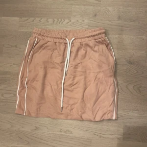 Rosa kjol med vita detaljer - Snygg rosa kjol med elastisk midja och vita snören. Kjolen har vita ränder längs sidorna. Ska flytta snart så vill gärna bli av med allt så fort som möjligt (pris kan diskuteras)💕