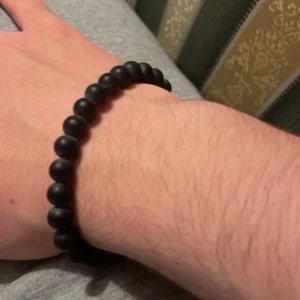 Marinblått pärlarmband - Snyggt svart armband med runda pärlor. En av pärlorna är brun, vilket ger en unik touch. Perfekt för att komplettera din stil.