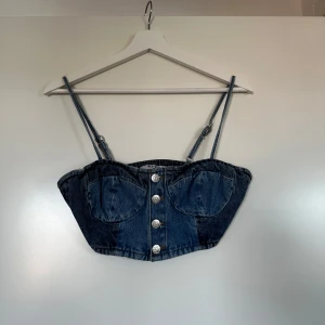 Jeans-topp från NA-KD - Supersnygg jeanstopp  från NA-KD med justerbara axelband och knappar framtill. Passar bra till både kjol och byxor. 💙