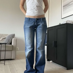 Blå jeans från Diesel - Säljer ett par snygga blå jeans från Diesel. De har en bootcut-stil och är lågmidjade, vilket ger en avslappnad look. Tillverkade i 100% bomull för en skön känsla. Perfekta för en casual outfit! Säljer då det är lite för långa och jag är 161cm!