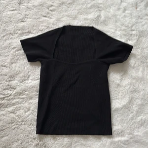 Svart ribbad topp - Snygg svart ribbad topp med korta ärmar och en elegant passform. Perfekt för en stilren look. köpt på en liten butik i paris för 300kr säljer för 100kr