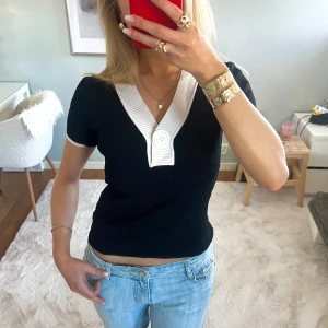 Svart kortärmad topp med vit krage - Otroligt snygg finstickad svart topp med korta ärmar och en vit ribbad krage & ärm-ändar med knappdetalj. Så bra kvalité, perfekt till ALLA tillfällen och sjukt fin💕storlek xs 