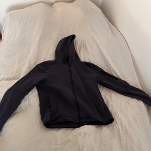 Nike tech fleece  - Säljer en stilren mörkblå nike tech med dragkedja. Perfekt för en vardaglig look samt till träning mm. Den har en praktisk huva och långa ärmar. Skriv om du har funderingar😁priset är ej hugget i sten.