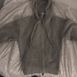 Grå hoodie från Zara - Säljer en mysig grå hoodie från Zara med dragkedja och justerbar huva. Tröjan har ribbade muddar vid ärmslut och nederkant, perfekt för en avslappnad stil. Passar bra till kyliga dagar. Jag säljer den då den inur kommer till användning och har bara använt den fåtal gånger💕