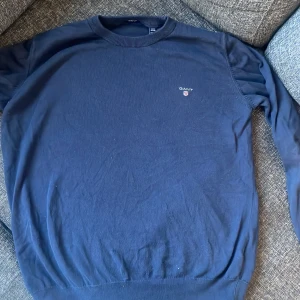 Mörkblå tröja från GANT - Säljer en stilren mörkblå tröja från GANT i 100% bomull. Tröjan har en klassisk rund halsringning och långa ärmar. Perfekt för en avslappnad och snygg look.