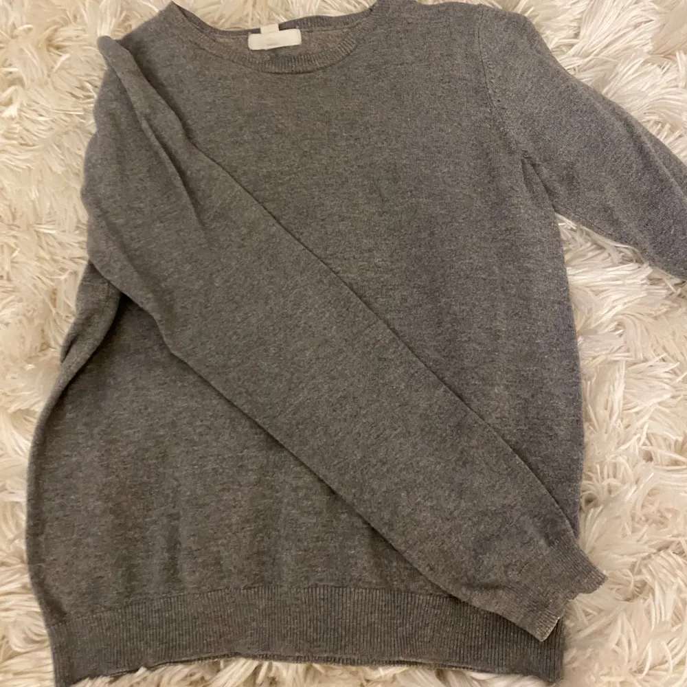 Säljer en stilren grå tröja från H&M Basics. Tröjan har en klassisk rund hals och långa ärmar, perfekt för en enkel och bekväm look. Ribbstickade muddar vid ärmslut och nederkant ger en snygg finish.. Neuletakit & Villapaidat.