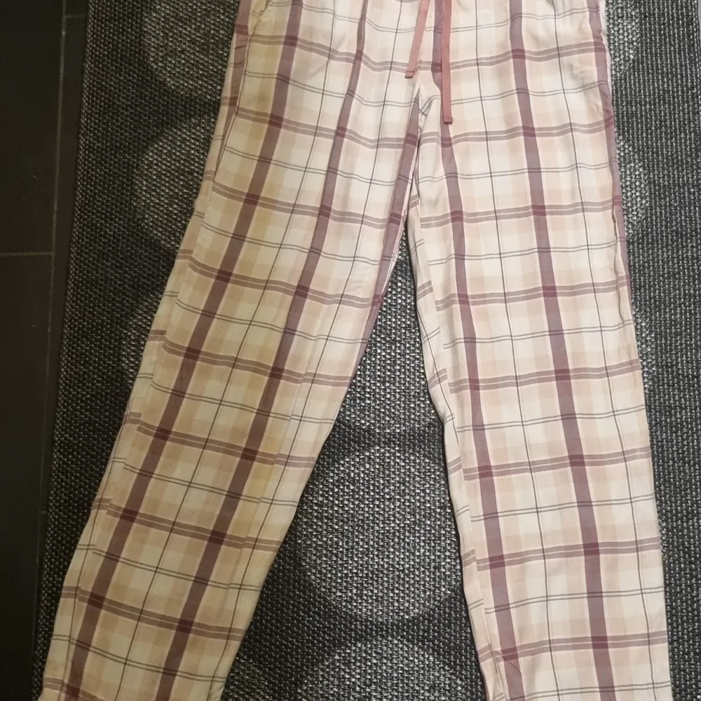 Mysiga rutiga byxor från Change i mjukt material. Byxorna har en bekväm elastisk midja med snörning för justerbar passform. Perfekta för en avslappnad dag hemma.. Farkut & Housut.