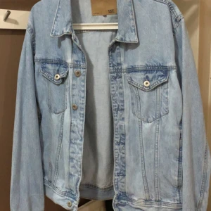 Ljusblå jeansjacka från 157 - Säljer en klassisk ljusblå jeansjacka från 157. Jackan har två bröstfickor med knappar och en stilren design. Perfekt för vår och sommar. 🧥