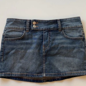 Blå jeanskjol - Snygg blå jeanskjol med klassisk femficksdesign och dubbla knappar fram. Väldigt fint skick och sparsamt använd. Skriv gällande funderingar🫶🏽