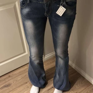 Blå bootcut jeans - Snygga blå bootcut jeans med låg midja och en lätt tvättad look. Omsydda.                     Midjemått: 36,5 cm Grenmått: 19 cm Innerbenslängd: 82 cm