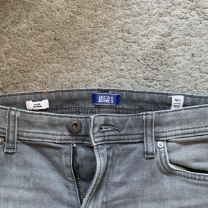Jack and Jones jeans - Gråa Jack and Jones jeans ganska så använd. Storlek 162. Slim fit/glenn. Kan sänka priset vid snabb affär. Den är lite sönder vid fickan dock, så därför detta pris.