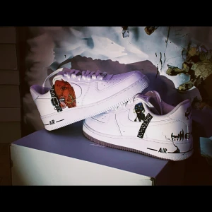 Unika vita sneakers med konstnärliga detaljer - Snygga vita Nike sneakers med unika konstnärliga detaljer som inkluderar en röd drake och blå eld. Skorna har en klassisk design med snörning och rund tå. Perfekta för den som vill sticka ut med sin stil.