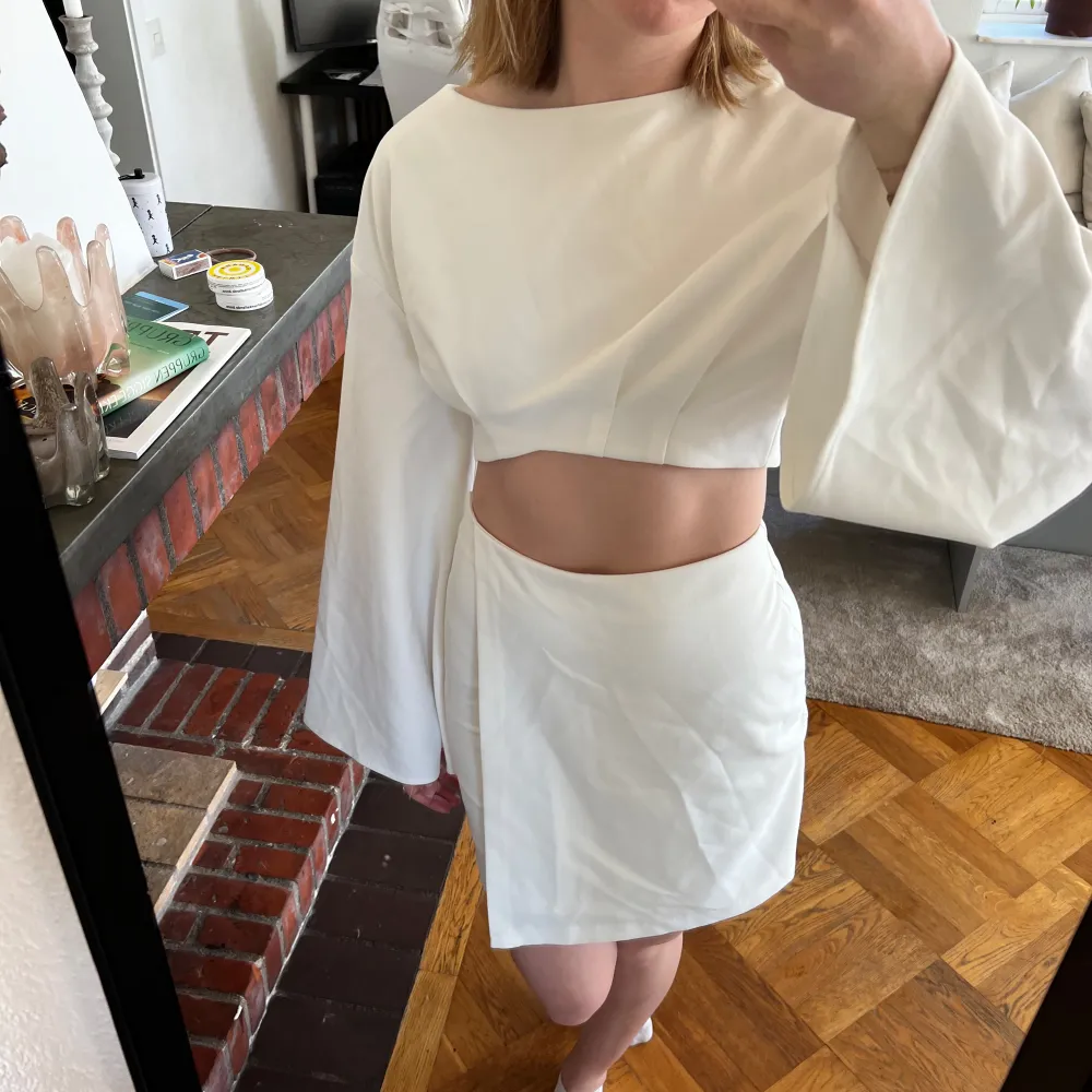 34 i kjolen, 36 i toppen! Snygg vit tvådelad klänning med långärmad topp och kort kjol. Toppen har vida ärmar och en croppad design som ger en modern look. Perfekt för en stilren och chic outfit. Perfekt till studenten! Hanna schönbergs kollektion med nakd! . Mekot.