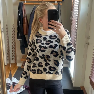 Leopardmönstrad stickad tröja från ONLY - Säljer en snygg stickad tröja från ONLY med leopardmönster i svart och beige. Tröjan har en rund halsringning och långa ärmar. Perfekt för att ge din outfit en trendig touch 🐆