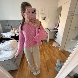 Rosa stickad tröja - Säljer en söt rosa stickad tröja med vida ärmar. Tröjan är croppad och har en avslappnad passform, perfekt för en mysig dag. Den ribbade strukturen ger en extra touch av stil. Perfekt för att hålla sig varm eller för fina sommarkvällar 💞