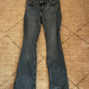Blå bootcut jeans från lager 157 - Säljer ett par snygga blå bootcut jeans från lager 157. De har en låg midja och klassisk femficksdesign. Perfekta för en avslappnad stil. Storlek S. 