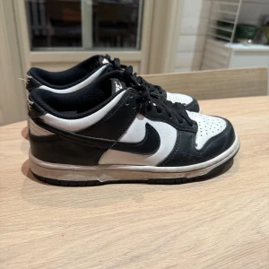 Svartvita Nike Dunk sneakers - Snygga svartvita Nike Dunk sneakers med klassisk design. Skorna har en rund tå och snörning framtill. Perfekta för en stilren look.