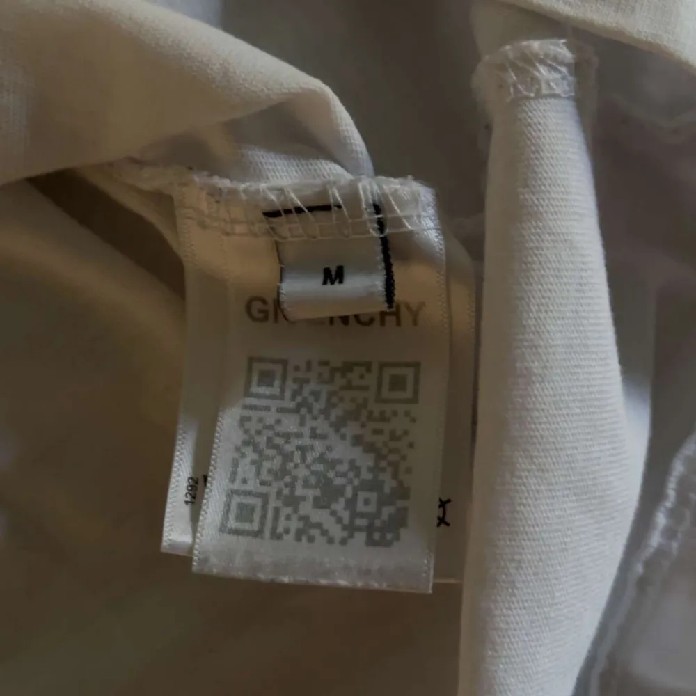 Säljer en stilren vit t-shirt från Givenchy med deras ikoniska logga tryckt i svart på bröstet. T-shirten har en klassisk rund hals och korta ärmar. Perfekt för en minimalistisk look.. T-paidat.