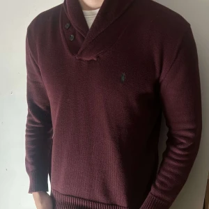 Vinröd tröja med krage och knappar - Snygg vinröd tröja med krage och dekorativa knappar. Perfekt för kyligare dagar med sin stilrena design och långa ärmar. Passar både till vardags och mer uppklädda tillfällen.