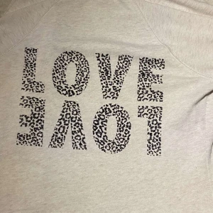 Victoria's Secret Zip Tröja - Säljer denna kofta från Victoria's Secret med texten 'LOVE' i leopardmönster på ryggen. Tröjan har en dragkedja framtill och två fickor. Köpt för flera år sen, finns ej kvar att köpa. Inga skador eller fläckar men lite ”använt” material pga tvättningar 🩷beige/vit färg!